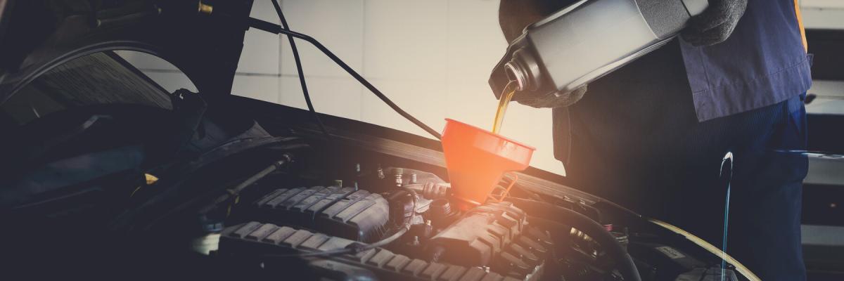 Changing the oil in a car engine, local auto mechanic filling your vehicle's oil with a funnel with the hood open