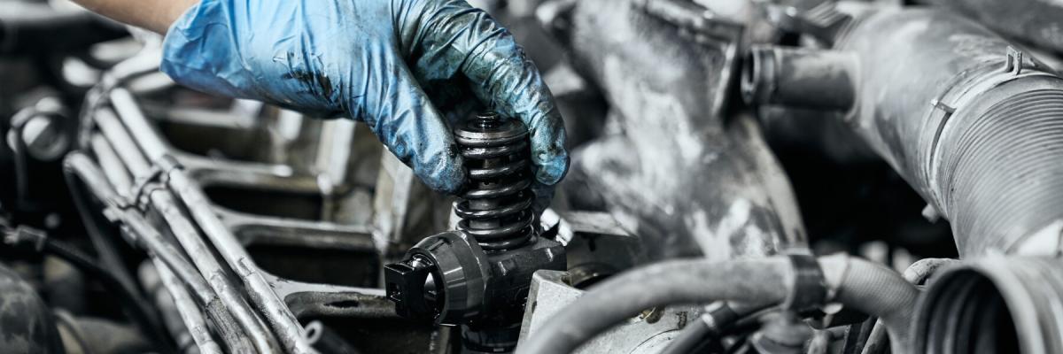 Professional mechanic in dirty protective gloves testing just installed nozzle into diesel car engine. Maintenance and repair concept for diesel engines