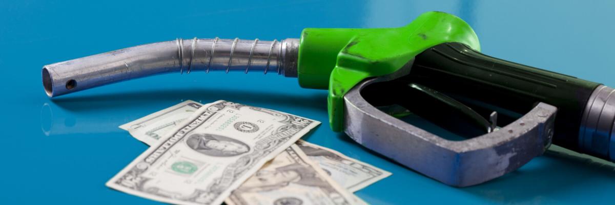 Gas price concept. American dollars and fuel nozzle